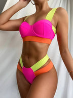 Modelo vestindo biquíni rosa pink com laranja e verde neon, top estruturado e calcinha cavada com tiras laterais largas.