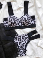 Biquíni estampa animal print preto e branco, top estruturado com alças largas pretas e calcinha com tiras laterais pretas.