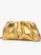 Bolsa clutch dourada metalizada com pregas profundas e corrente dourada sobre fundo branco.
