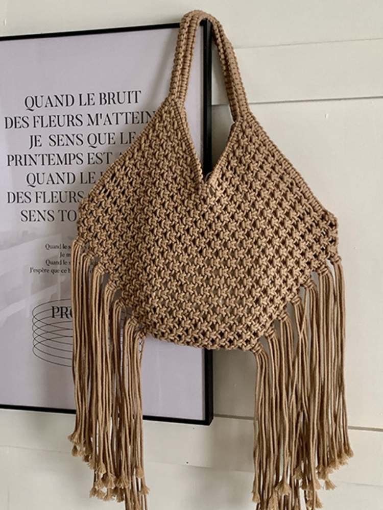 bolsa feminina de ombro em macramê bege com franjas pendurada na parede