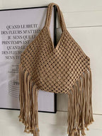 bolsa feminina de ombro em macramê bege com franjas pendurada na parede