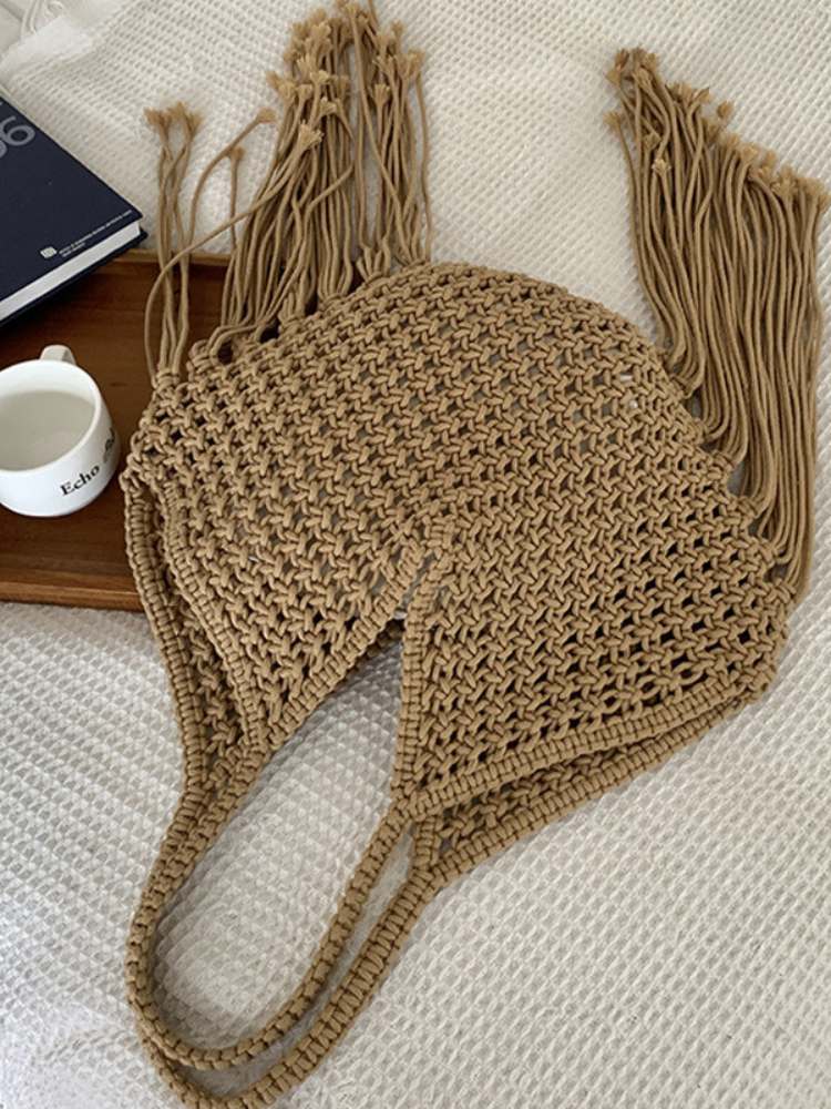 bolsa feminina de ombro em macramê bege com franjas longas exibida sobre superfície branca