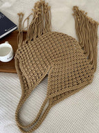 bolsa feminina de ombro em macramê bege com franjas longas exibida sobre superfície branca