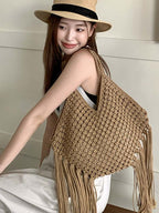 bolsa de macramê bege com franjas usada no ombro por modelo com chapéu de palha
