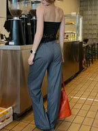 Calça feminina cinza com risca de giz vista por trás em ambiente de cafeteria
