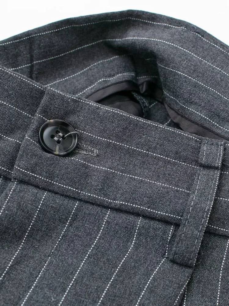 Detalhe do cós e botão da calça de alfaiataria cinza com risca de giz
