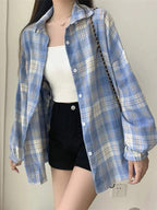 Camisa xadrez feminina em tons de azul claro e branco, usada aberta sobre top branco e shorts preto, estilo casual minimalista.