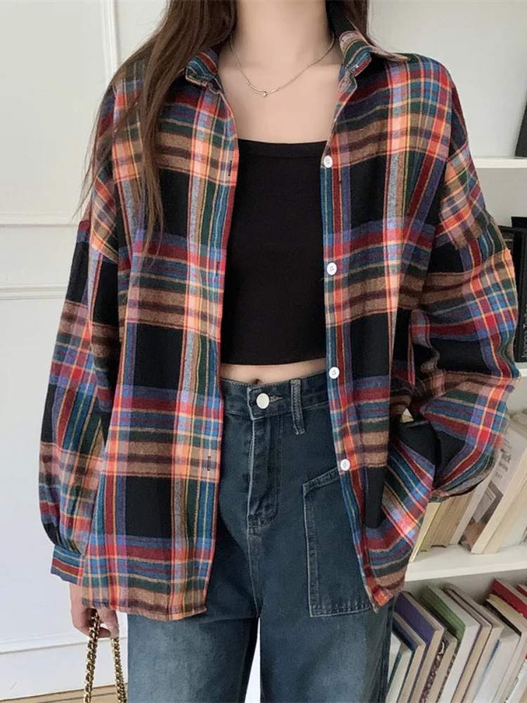Camisa xadrez feminina com mix de cores escuras e vibrantes, incluindo preto, azul e vermelho, usada com top preto cropped e calça jeans, estilo despojado.