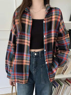 Camisa xadrez feminina com mix de cores escuras e vibrantes, incluindo preto, azul e vermelho, usada com top preto cropped e calça jeans, estilo despojado.