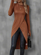 lamiseta feminina longa estilo túnica em tecido marrom com manga longa e corte transpassado frontal, usada com calça preta justa
