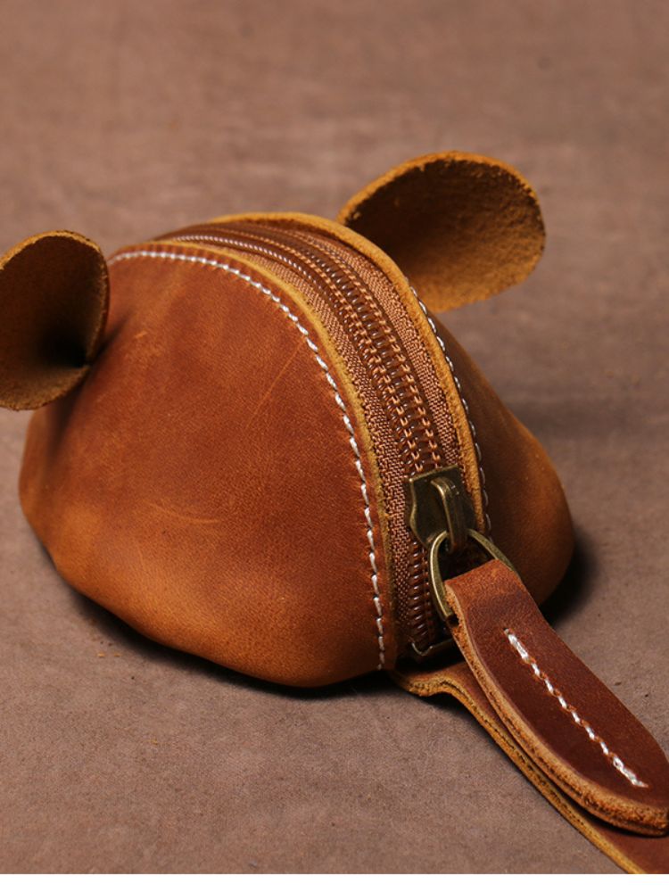 Vista traseira da bolsa pequena em formato de ratinho feita em couro caramelo com zíper metálico
