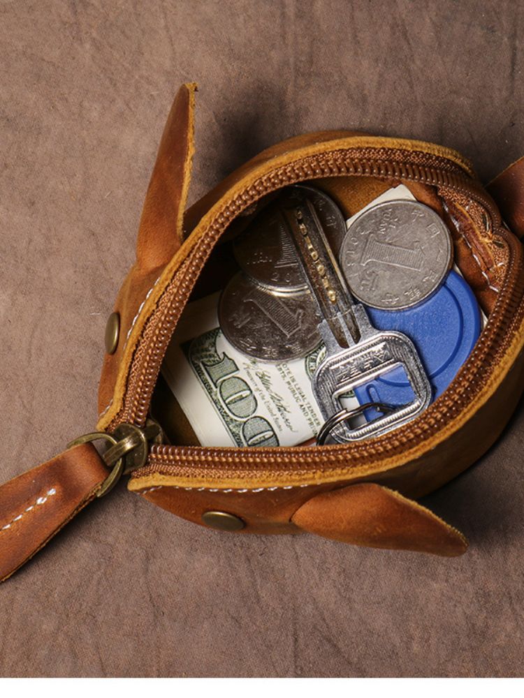 Bolsa pequena em formato de ratinho aberta contendo moedas, notas e chaves
