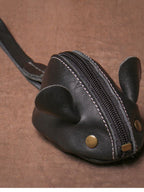 Bolsa pequena em formato de ratinho feita em couro preto com rebites metálicos e alça de mão
