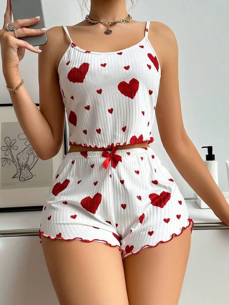 Conjunto de pijama feminino branco com corações vermelhos, top cropped de alças finas e shorts curto com babado e laço vermelho na cintura.