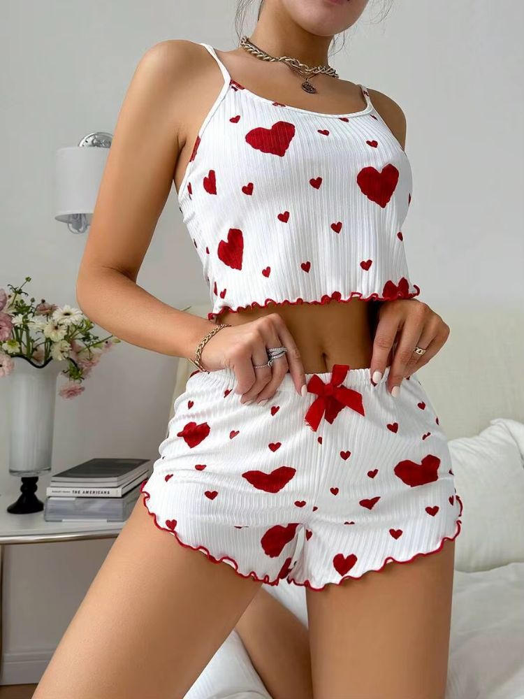 Pijama feminino branco estampado com corações vermelhos, top cropped de alças finas e shorts curto com laço vermelho na cintura e acabamento ondulado.