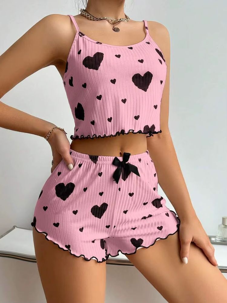 Pijama feminino rosa com estampa de corações pretos, top cropped de alças finas e shorts curto com laço preto na cintura e acabamento ondulado.