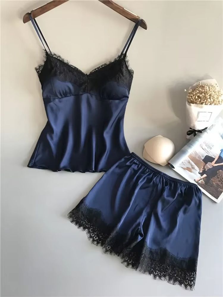 Conjunto de pijama feminino em cetim azul marinho com top de alças e renda preta no busto, ao lado de short azul marinho com renda preta na barra.