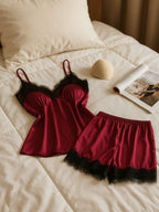 Conjunto de pijama feminino em cetim vinho com renda preta disposto sobre cama clara, ao lado de acessório e revista.