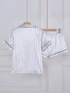 Conjunto de pijama feminino em cetim cinza listrado, visto de costas, com camisa de manga curta e shorts combinando.