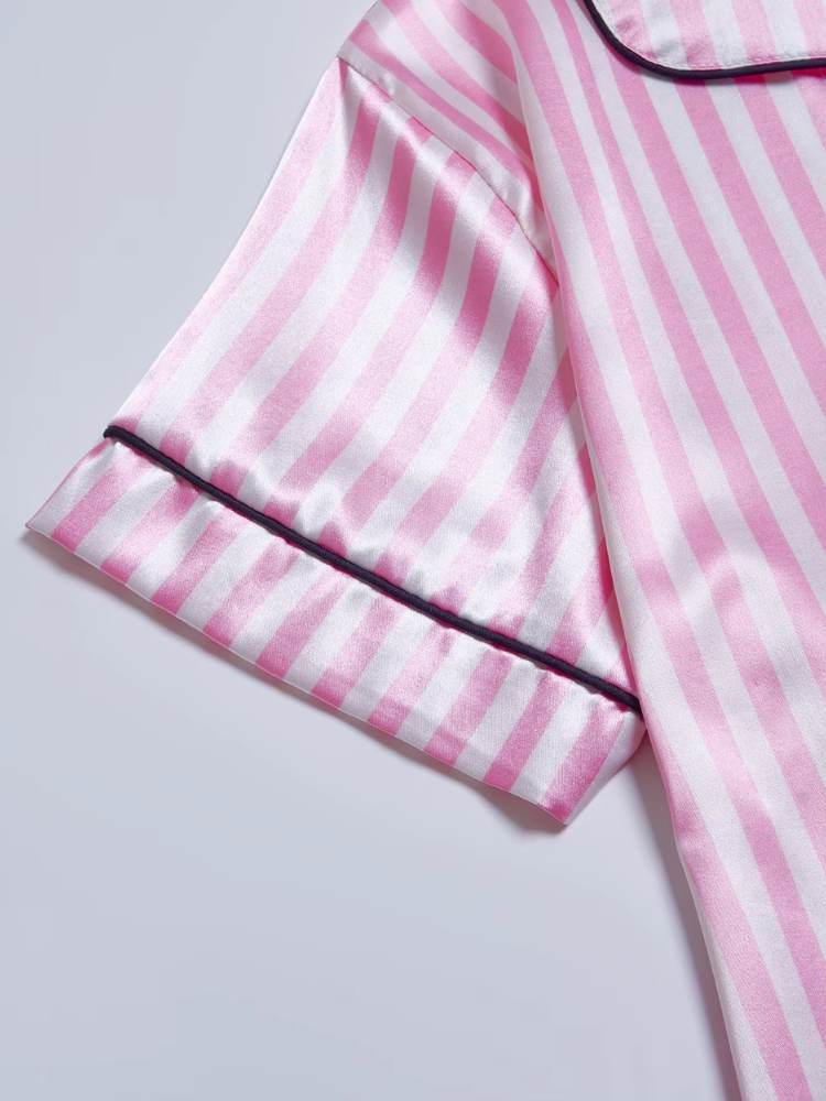 Detalhe da manga do pijama de cetim rosa listrado com vivo preto no acabamento.