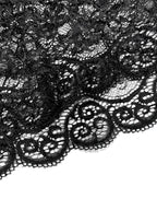 Close detalhado do tecido de renda preta com desenho floral e bordas onduladas.