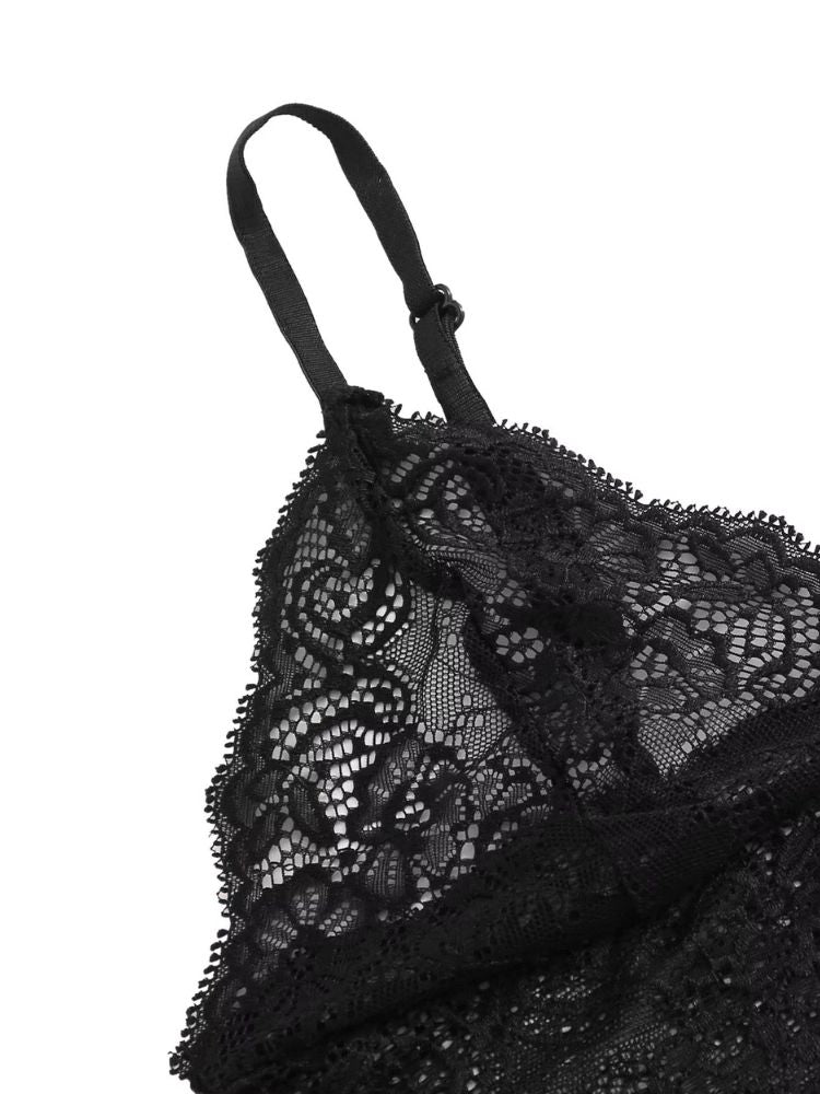  Close do top de renda preto com alça fina ajustável, exibindo detalhes florais da renda.