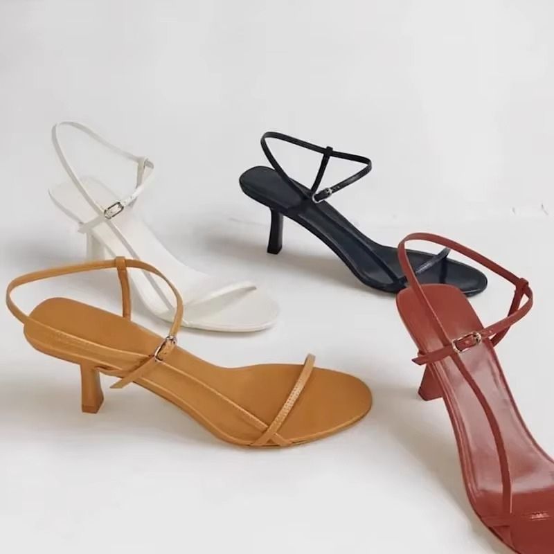 Sandália feminina de salto médio fino com tiras delicadas e design minimalista, disponível em branco, preto, caramelo e vermelho.