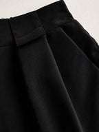 Detalhe do shorts preto mostrando pregas frontais e textura do tecido de alfaiataria
