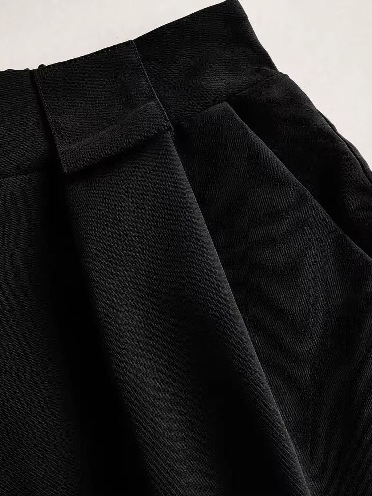 Detalhe do shorts preto mostrando pregas frontais e textura do tecido de alfaiataria
